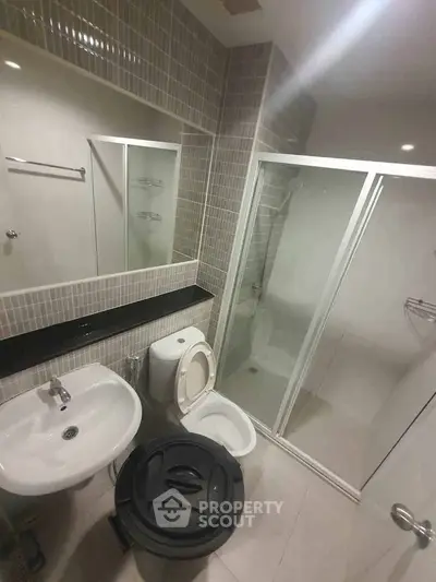 Modern bathroom with glass shower enclosure and sleek fixtures in a contemporary apartment.