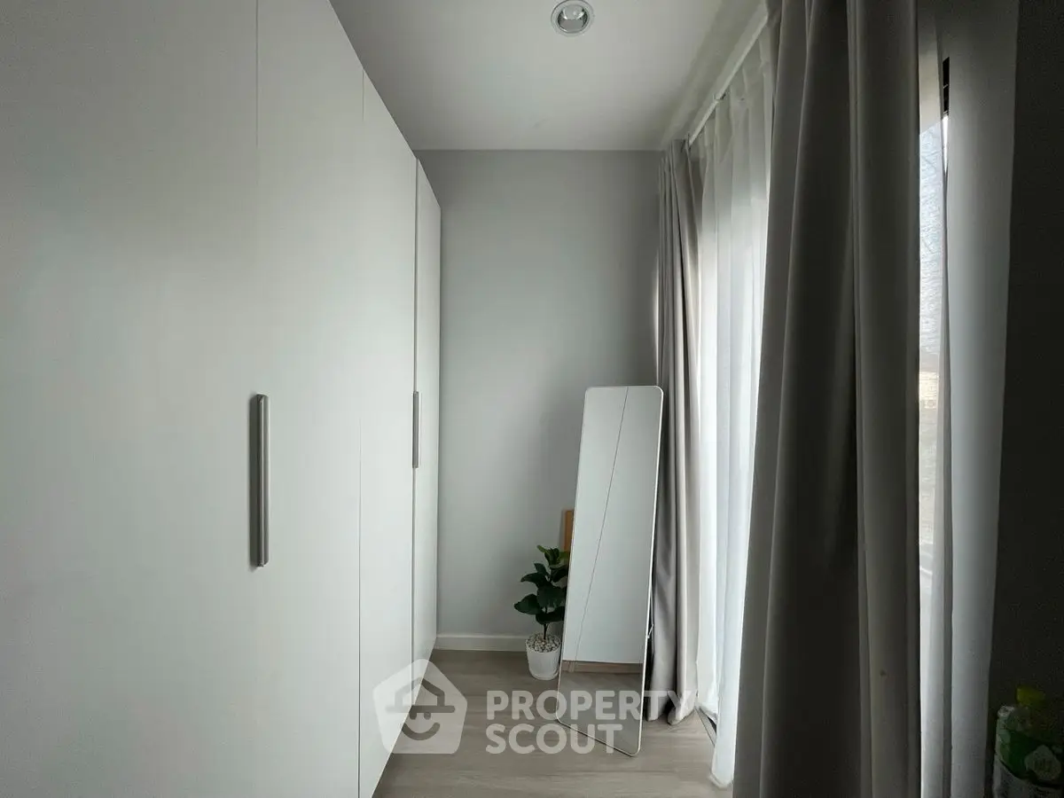 Modern minimalist bedroom with sleek wardrobe and full-length mirror