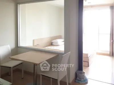 Modern apartment interior with dining area and bedroom, featuring minimalist design and natural light.