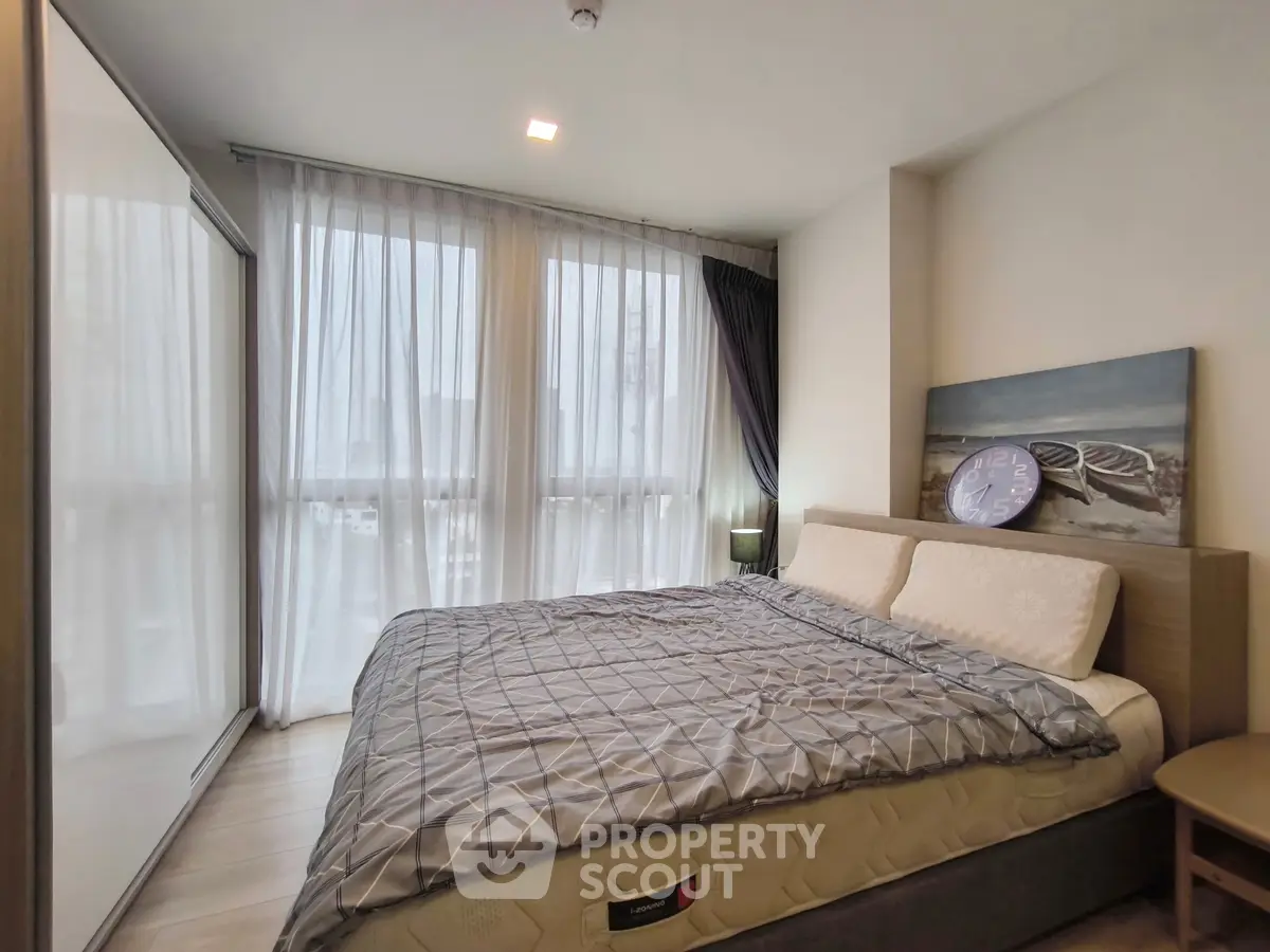 Modern bedroom with large windows and stylish decor in a contemporary apartment.