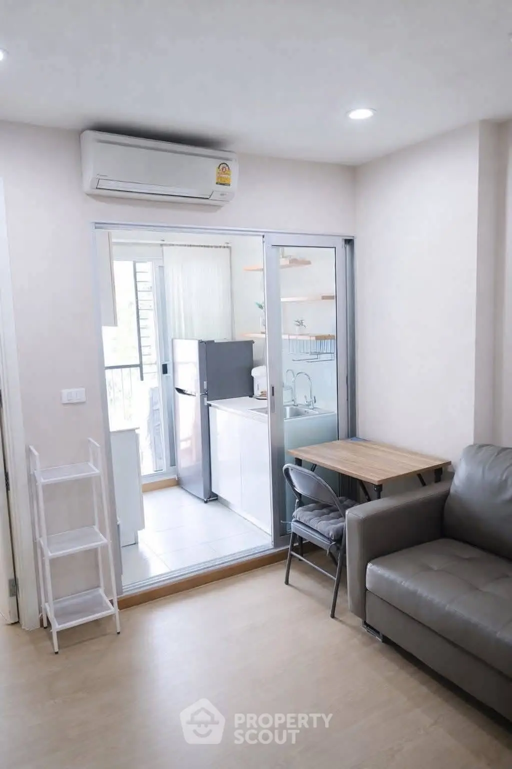 Modern living room with sliding glass doors leading to a compact kitchen, featuring sleek appliances and cozy seating.