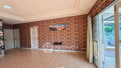 Spacious living room with brick accent wall and large windows for natural light.