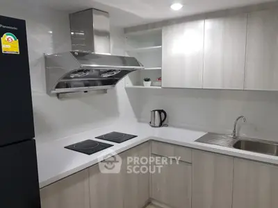 Modern kitchen with sleek cabinets, electric stove, and stainless steel range hood.