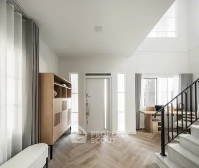 Modern living room with stylish furniture and natural light, featuring a staircase and elegant wood flooring.