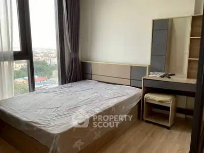 Cozy bedroom with large windows and city view, featuring modern furniture and natural light.