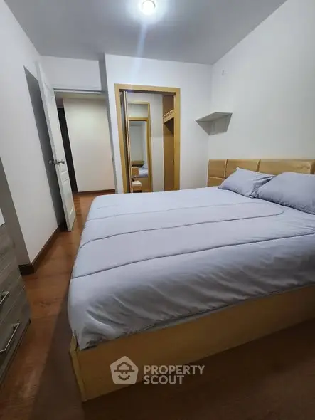 Cozy bedroom with wooden flooring and modern furniture, perfect for relaxation and comfort.