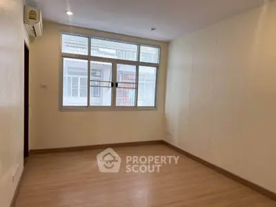 Spacious empty room with large window and wooden flooring, ideal for customization.