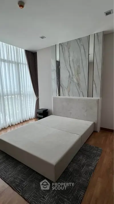 Luxurious bedroom with floor-to-ceiling windows and elegant marble accent wall.