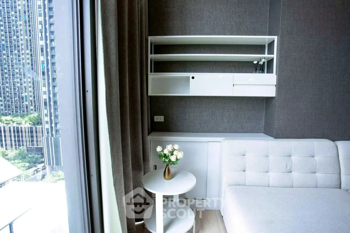 Modern living room with sleek white furniture and large window view in urban apartment.