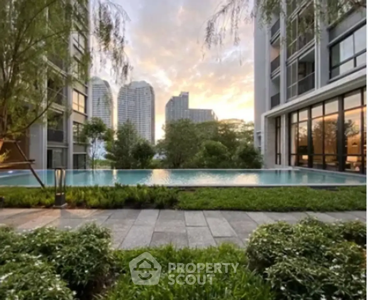 Luxurious apartment complex with stunning pool and city skyline view at sunset.