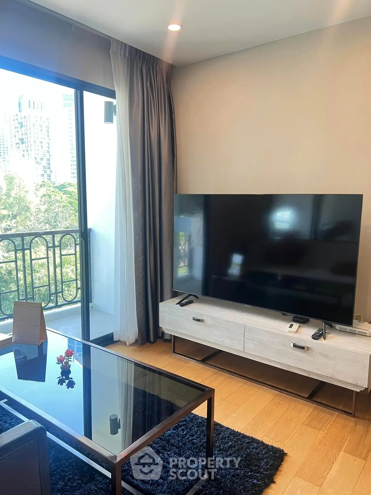 Modern living room with large TV and balcony view in upscale apartment.