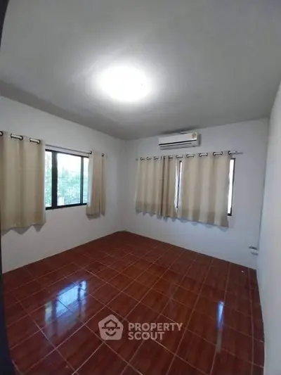 Spacious bedroom with tiled floor and large windows for natural light.