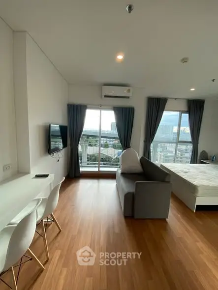 Modern studio apartment with open layout and city view, featuring a cozy living area and sleek furnishings.