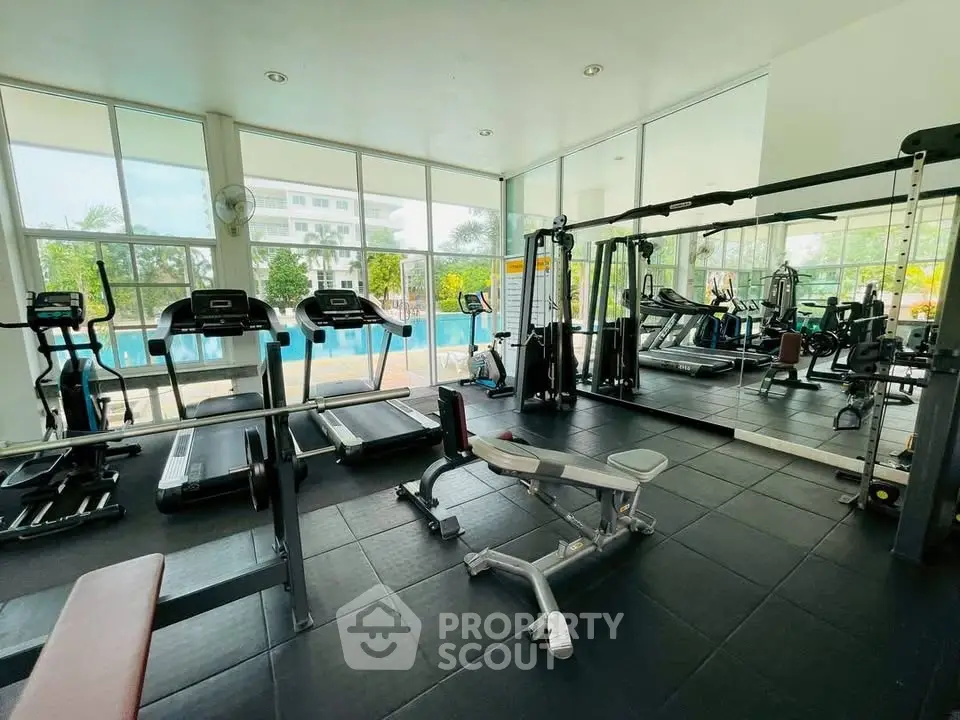 Modern gym with pool view, featuring state-of-the-art equipment and spacious workout area.