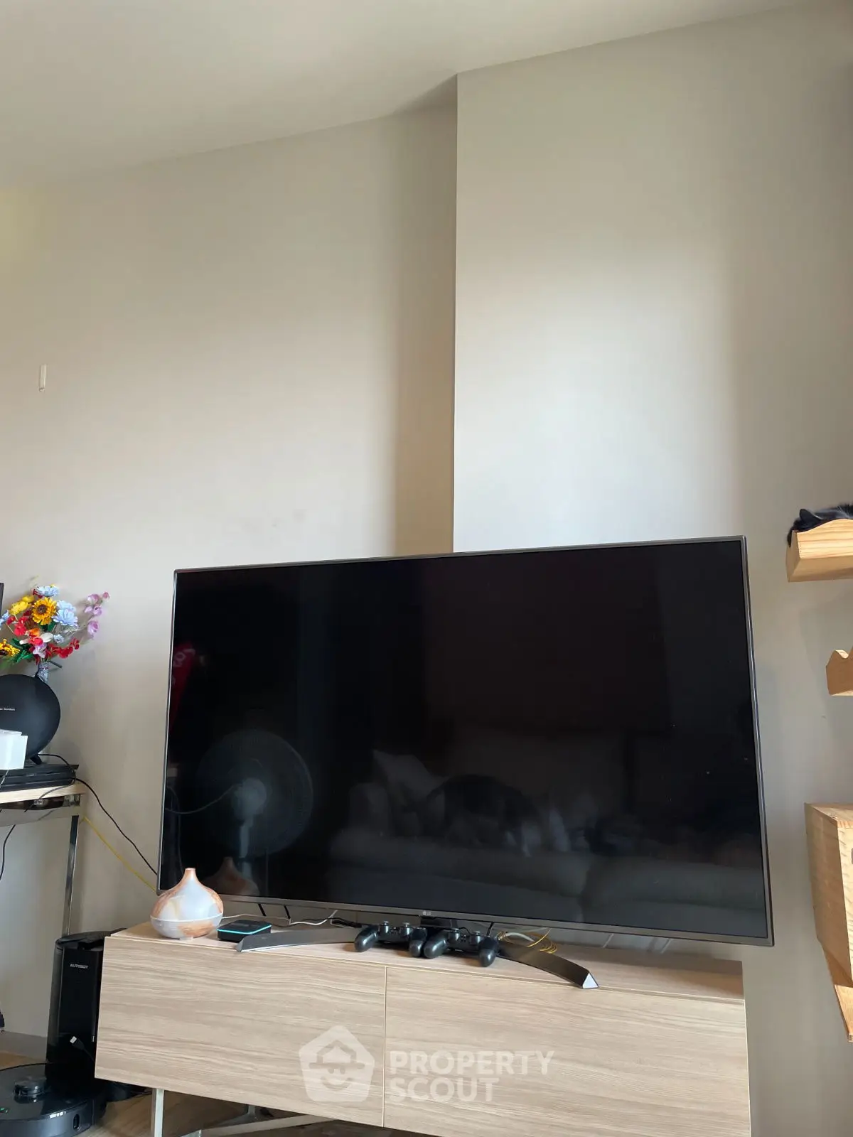 Modern living room with large flat-screen TV and stylish wooden console.