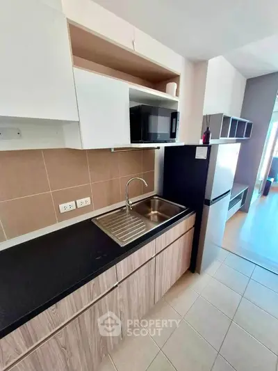 Modern kitchen with sleek cabinetry and stainless steel sink in a contemporary apartment.