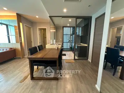 Modern open-plan living and dining area with sleek wooden furniture and glass partitions.