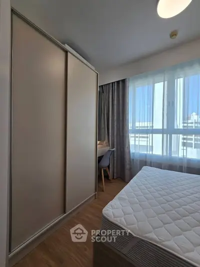 Modern bedroom with large window and built-in wardrobe, offering ample natural light and cozy ambiance.