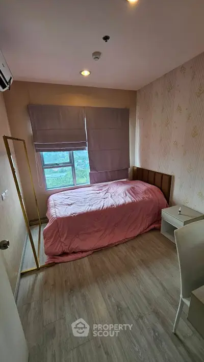 Cozy bedroom with pink bedding and modern decor, featuring a large window and stylish furnishings.