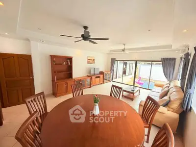 Spacious living room with elegant wooden furniture and pool view, perfect for family gatherings.