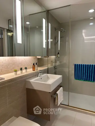 Modern bathroom with glass shower, sleek vanity, and ambient lighting