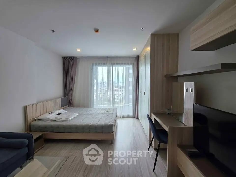 Modern bedroom with city view, featuring sleek furniture and natural light.