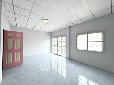 Spacious empty room with tiled floor and large windows, perfect for customization.