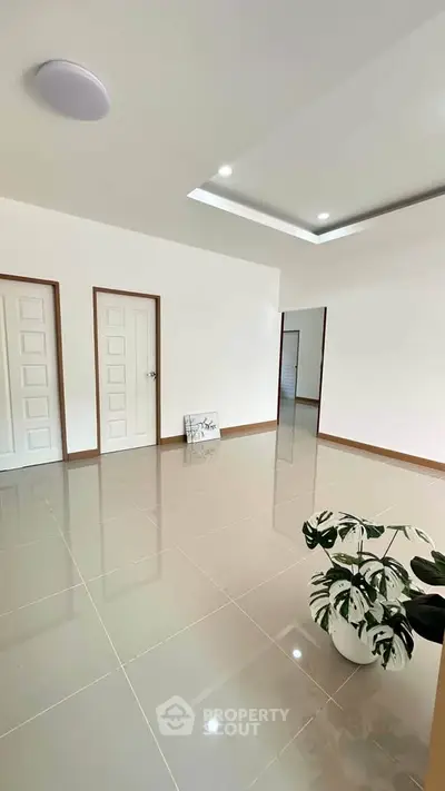 Spacious modern interior with glossy tiled floors and elegant recessed lighting, perfect for contemporary living.