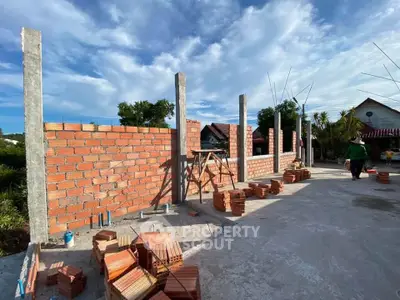 Construction site with brick walls under blue sky, showcasing early stages of building development.