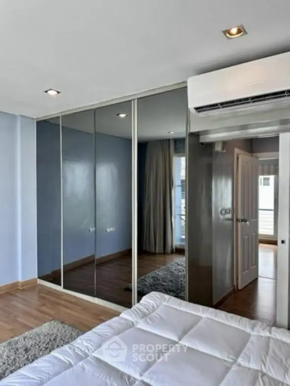 Modern bedroom with mirrored wardrobe and air conditioning unit