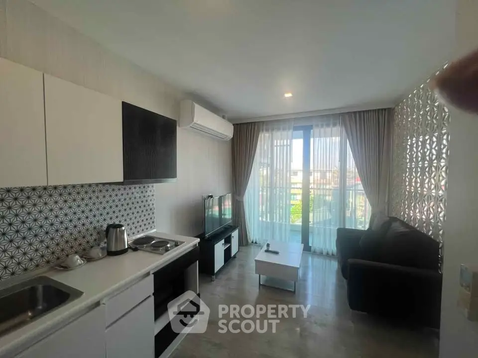 Modern living room with open kitchen, stylish decor, and natural light from large windows.