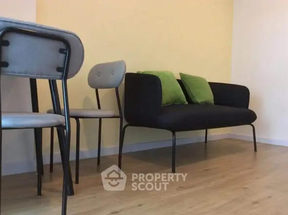 Modern minimalist living room with stylish black sofa and green cushions, perfect for cozy relaxation.