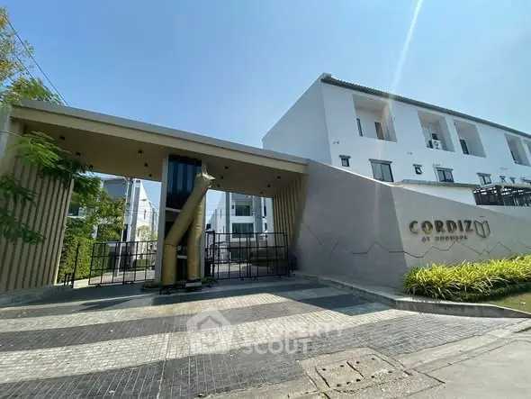 Modern residential building entrance with sleek design and clear blue sky.