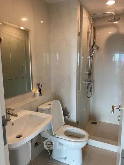 Modern bathroom with sleek fixtures and glass shower enclosure in a contemporary apartment.