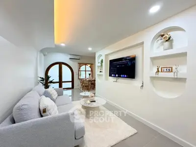 Modern living room with stylish decor, cozy sofa, and wall-mounted TV, perfect for relaxation and entertainment.