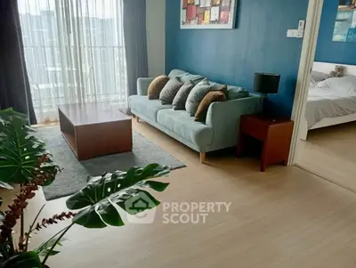 Modern living room with stylish sofa and natural light, adjacent to a cozy bedroom.