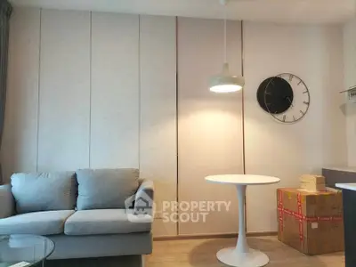 Modern living room with stylish sofa and round table, featuring elegant wall clock and ambient lighting.