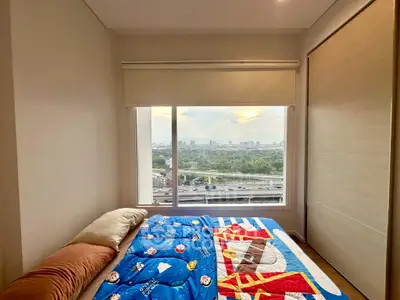 Cozy bedroom with large window offering stunning cityscape view, perfect for relaxation and comfort.