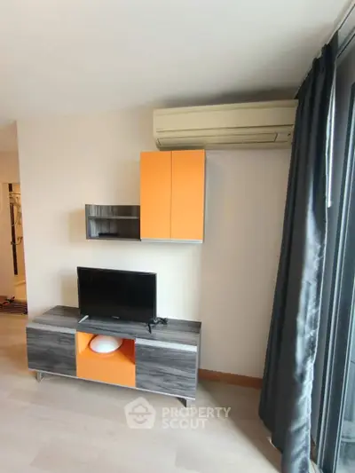 Modern living room with stylish TV stand and air conditioning unit, featuring sleek design and vibrant accents.
