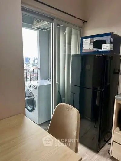 Modern apartment with balcony, featuring a sleek black fridge and washing machine, offering city views.