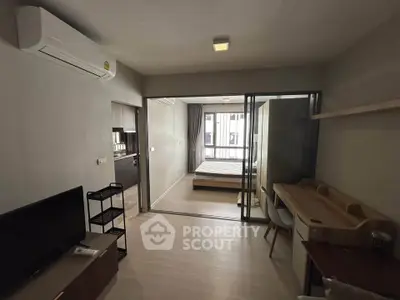 Modern apartment interior with open layout, featuring a cozy living area and a stylish bedroom separated by glass doors.