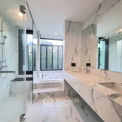 Luxurious marble bathroom with modern fixtures and large windows.