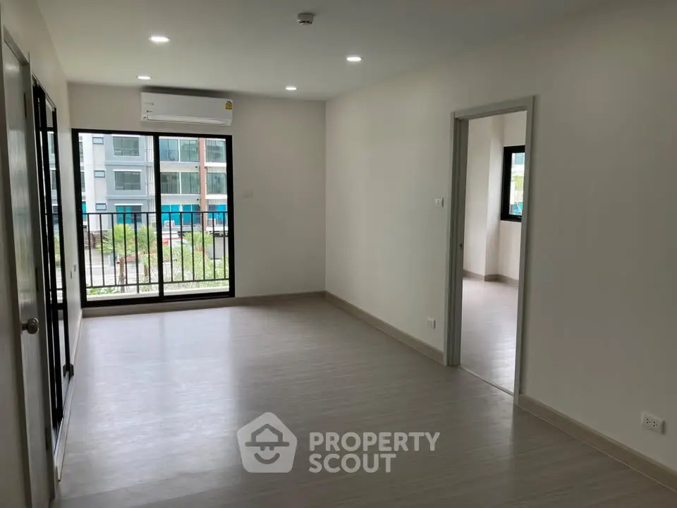 Spacious modern apartment with large windows and sleek flooring, offering abundant natural light.