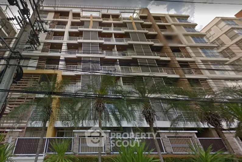 Modern multi-story apartment building with palm trees and sleek design.