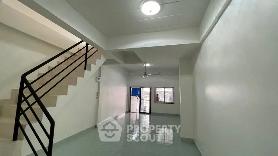 Spacious open-plan living area with staircase and large windows for natural light.