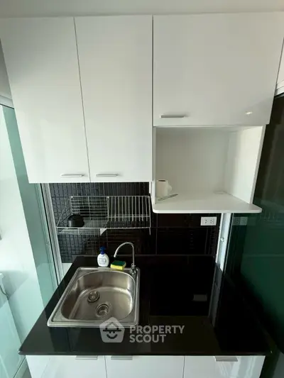 Modern compact kitchen with sleek black countertop and stainless steel sink