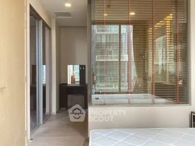 Modern bedroom with glass partition and ensuite bathroom featuring a luxurious bathtub.