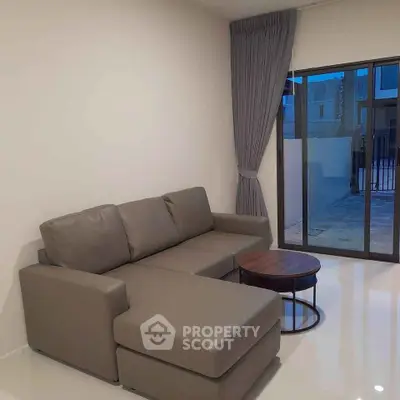 Modern living room with sleek gray sofa and glass sliding doors leading to outdoor area.