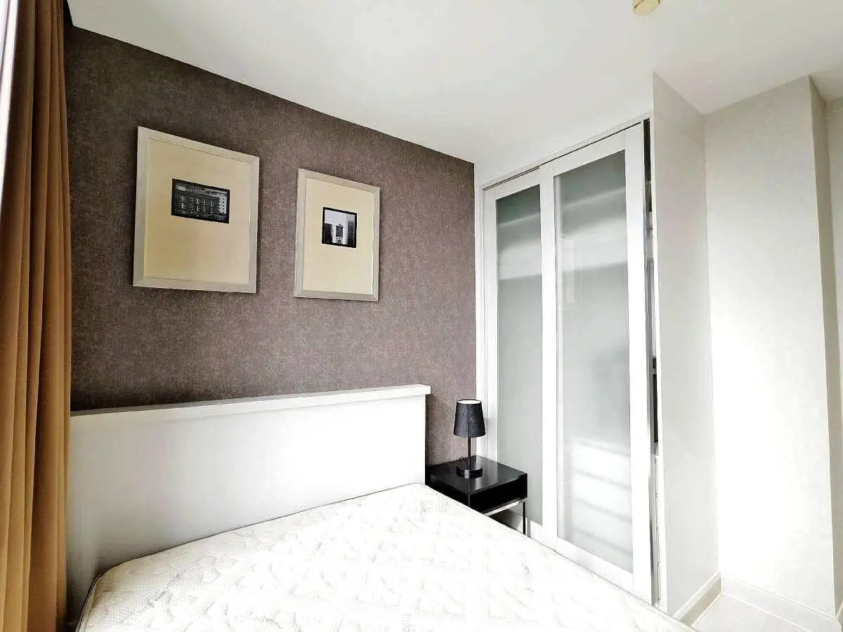 Modern bedroom with stylish decor and ample natural light, featuring a comfortable bed and sleek storage solutions.