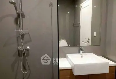 Modern bathroom with sleek fixtures and minimalist design, featuring a glass shower and contemporary sink.